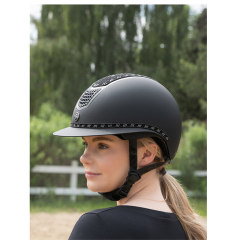 Person wearing a black riding helmet with a blurred green background