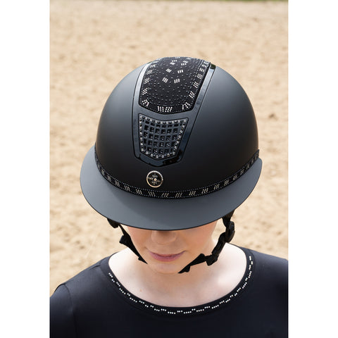 Person wearing a black equestrian helmet with decorative patterns on a beige background